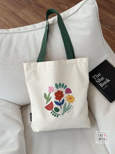 White tote bag with floral design on a white couch