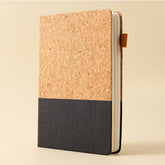 Notebook with cork cover and black fabric bottom on a beige background