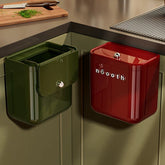 Green and red kitchen trash bins hanging on a cabinet door.